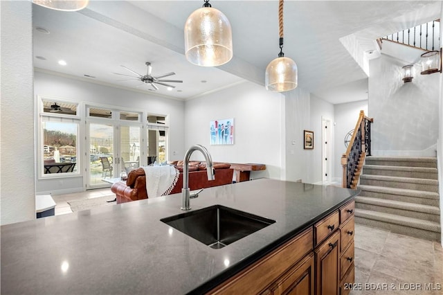 kitchen with ceiling fan, open floor plan, brown cabinets, hanging light fixtures, and a sink