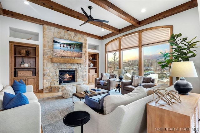 living area featuring a ceiling fan, beam ceiling, built in shelves, and a fireplace