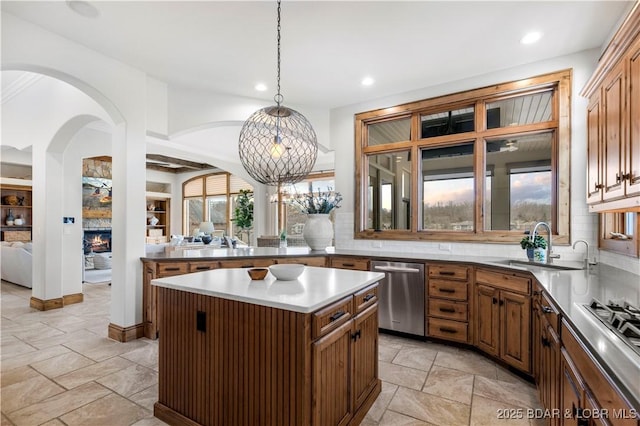 kitchen with tasteful backsplash, a center island, decorative light fixtures, a warm lit fireplace, and stainless steel appliances