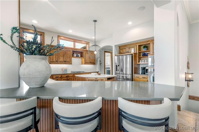 kitchen featuring arched walkways, decorative backsplash, stainless steel fridge, and open shelves