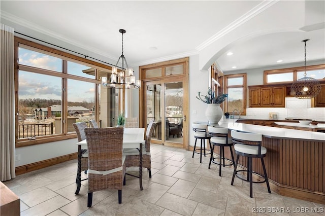 dining room featuring baseboards, recessed lighting, arched walkways, ornamental molding, and a chandelier