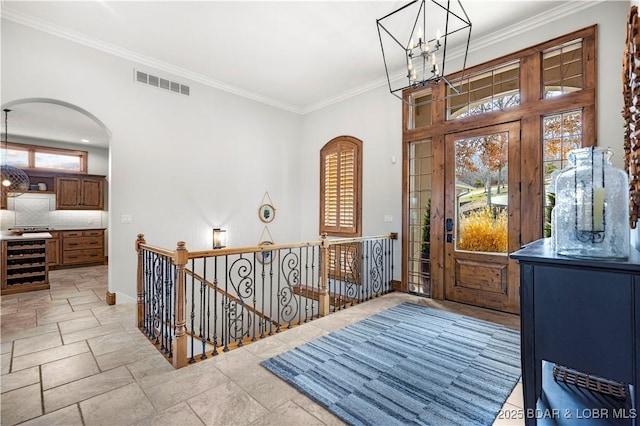 foyer with a chandelier, visible vents, wine cooler, and arched walkways