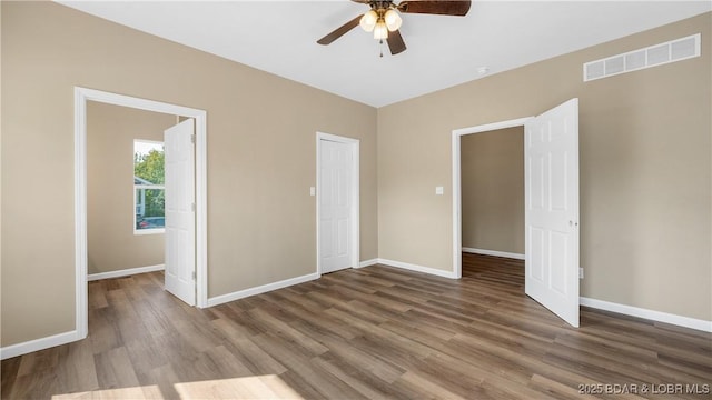 unfurnished bedroom featuring ceiling fan, visible vents, baseboards, and wood finished floors