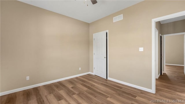 unfurnished room with a ceiling fan, wood finished floors, baseboards, and visible vents