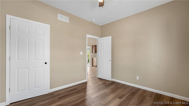 unfurnished bedroom with a ceiling fan, wood finished floors, baseboards, and visible vents