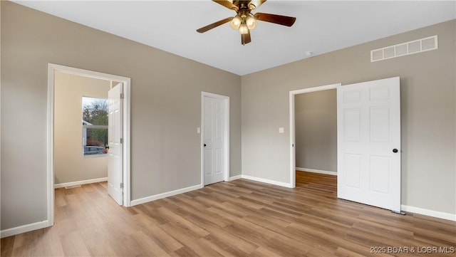 unfurnished bedroom featuring light wood-type flooring, visible vents, baseboards, and ceiling fan