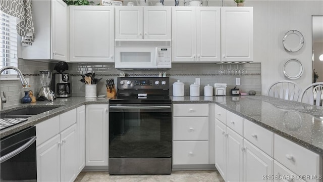 kitchen featuring dishwashing machine, white microwave, a sink, electric range oven, and white cabinetry