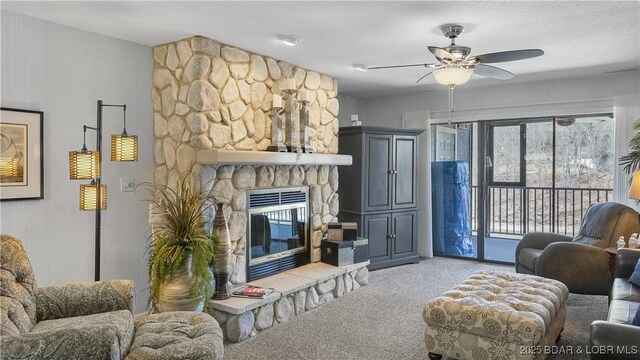 living room featuring carpet flooring, a fireplace, and ceiling fan