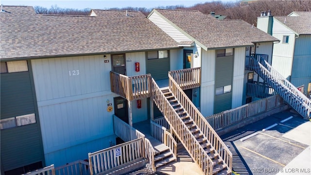 view of front of home with stairway and roof with shingles