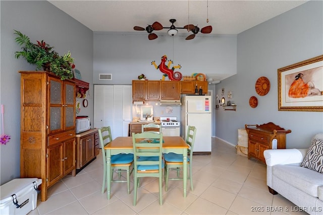 dining area featuring light tile patterned floors, visible vents, a towering ceiling, and ceiling fan