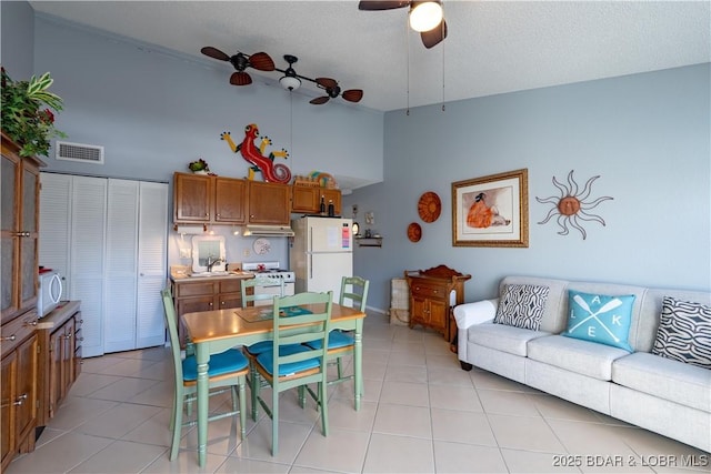 dining room featuring visible vents, ceiling fan, high vaulted ceiling, light tile patterned flooring, and a textured ceiling