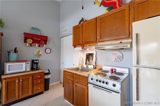 kitchen with white appliances, light tile patterned flooring, a sink, light countertops, and under cabinet range hood