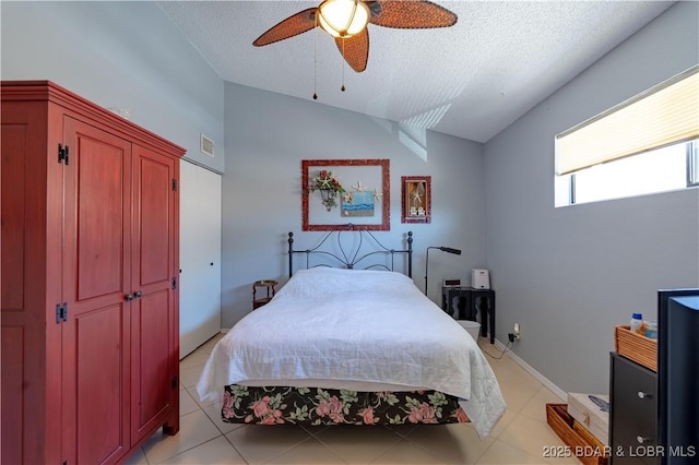 bedroom with visible vents, vaulted ceiling, light tile patterned floors, a textured ceiling, and a ceiling fan