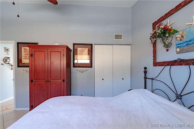 bedroom featuring tile patterned floors, visible vents, baseboards, and a closet