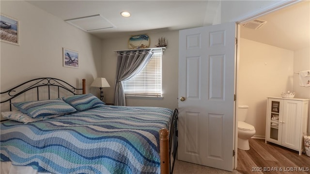 bedroom with visible vents, attic access, recessed lighting, ensuite bathroom, and wood finished floors