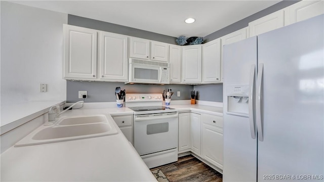 kitchen featuring white appliances, white cabinets, light countertops, and a sink