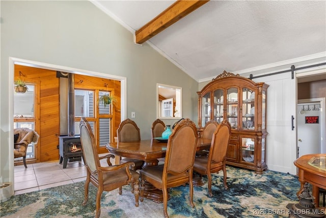 tiled dining space featuring a barn door, a wood stove, vaulted ceiling with beams, and crown molding