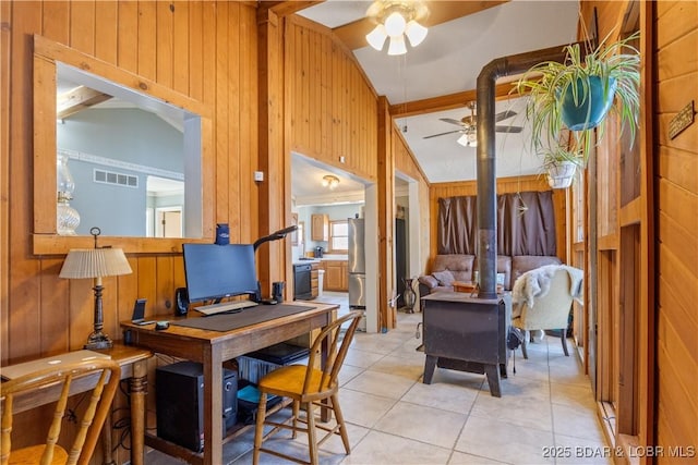 office area with visible vents, lofted ceiling, a wood stove, and wooden walls