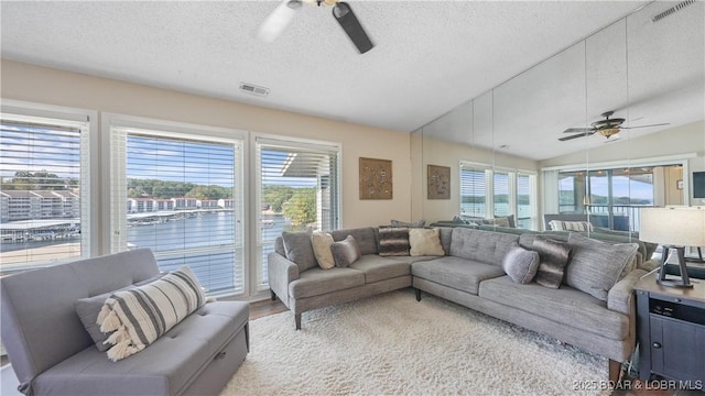 living area with vaulted ceiling, visible vents, a wealth of natural light, and ceiling fan