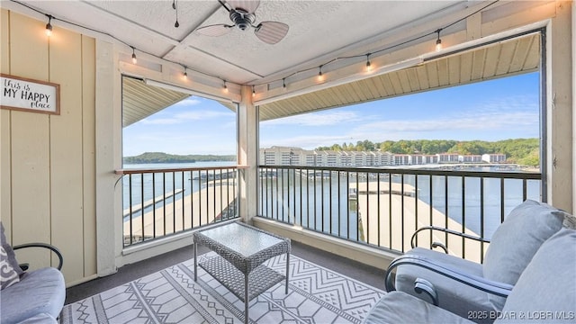 balcony featuring a water view and ceiling fan