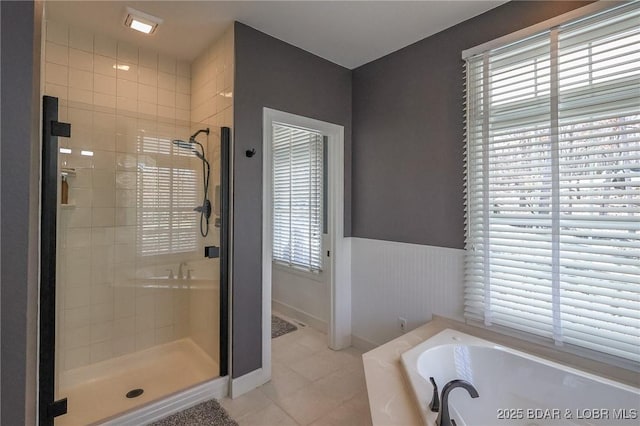 bathroom featuring a bath, a wainscoted wall, a shower stall, and tile patterned flooring