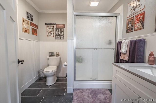 full bath featuring a wainscoted wall, toilet, a stall shower, and crown molding
