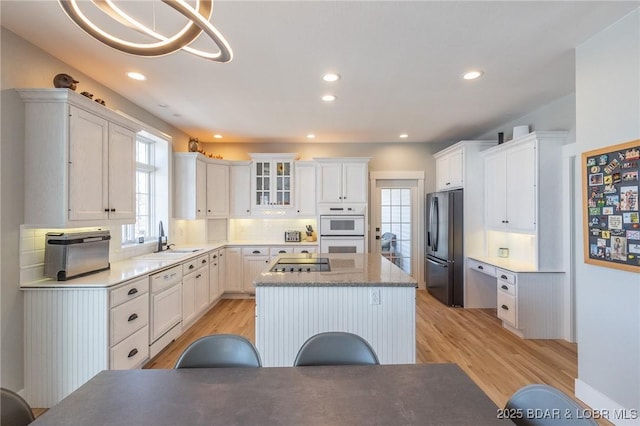 kitchen with a center island, decorative backsplash, light wood-style floors, white cabinets, and white appliances