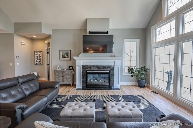 living room featuring visible vents, a fireplace, baseboards, and wood finished floors