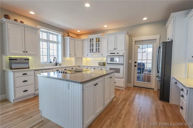 kitchen featuring plenty of natural light, white cabinets, appliances with stainless steel finishes, and light wood-style flooring