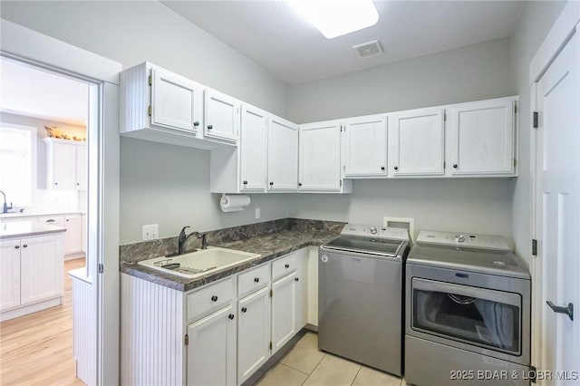 laundry room with light wood finished floors, visible vents, washer and clothes dryer, cabinet space, and a sink