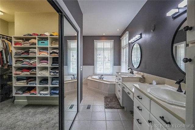 full bathroom featuring double vanity, a sink, a spacious closet, tile patterned floors, and a bath