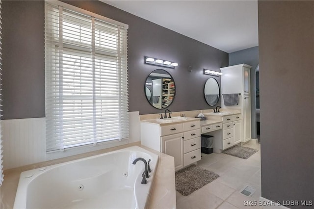full bathroom featuring a wealth of natural light, a jetted tub, vanity, and tile patterned floors