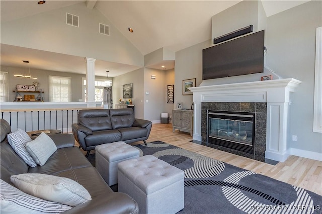 living room featuring light wood finished floors, visible vents, and beamed ceiling