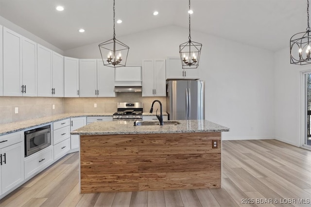 kitchen featuring light wood finished floors, an inviting chandelier, a sink, appliances with stainless steel finishes, and backsplash