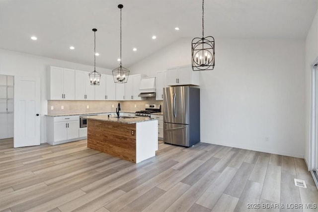 kitchen with light wood finished floors, a sink, stainless steel appliances, white cabinets, and backsplash