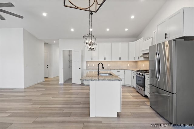 kitchen featuring light wood-type flooring, a sink, stainless steel appliances, decorative backsplash, and light stone countertops