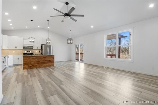 kitchen with light wood finished floors, appliances with stainless steel finishes, exhaust hood, ceiling fan with notable chandelier, and open floor plan