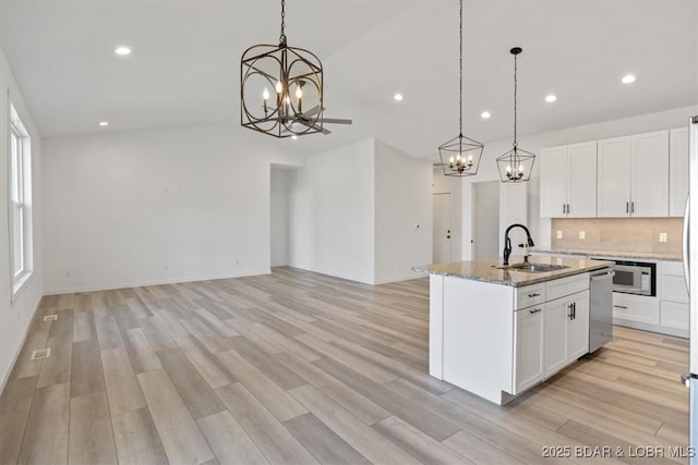 kitchen with a chandelier, decorative backsplash, light wood-style flooring, and a sink