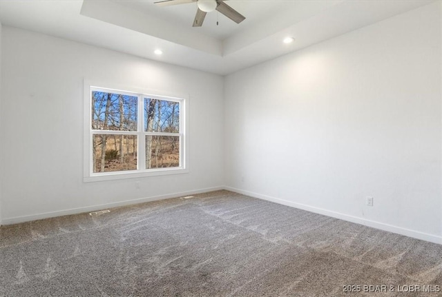 carpeted empty room with a ceiling fan, a tray ceiling, recessed lighting, and baseboards