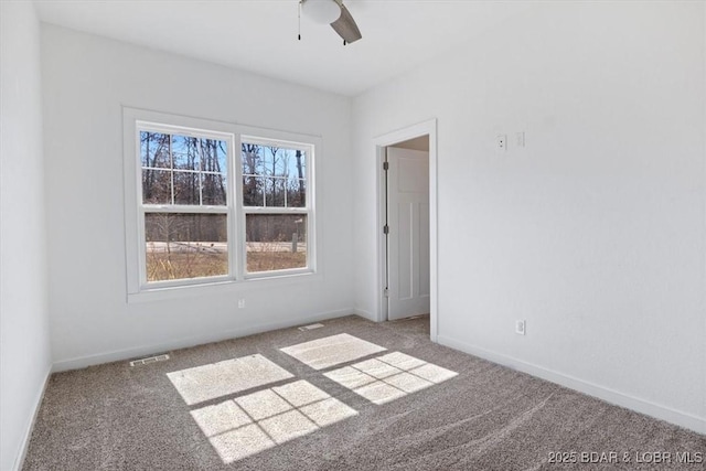 carpeted spare room featuring visible vents, baseboards, and ceiling fan