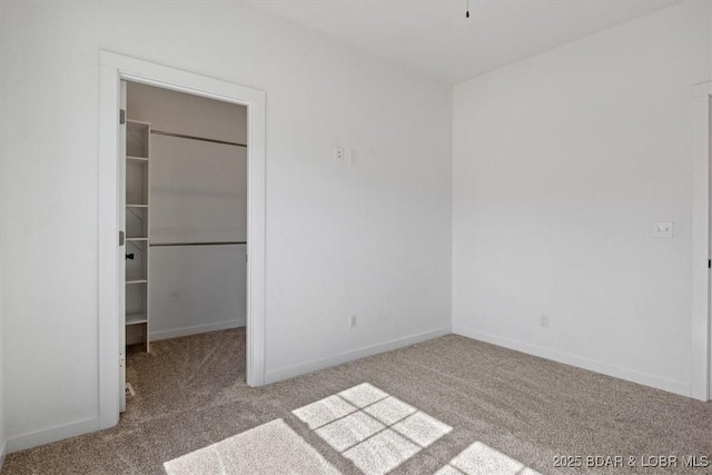 unfurnished bedroom with a closet, carpet floors, and a spacious closet