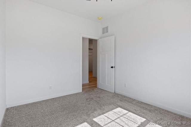 carpeted spare room featuring visible vents and baseboards