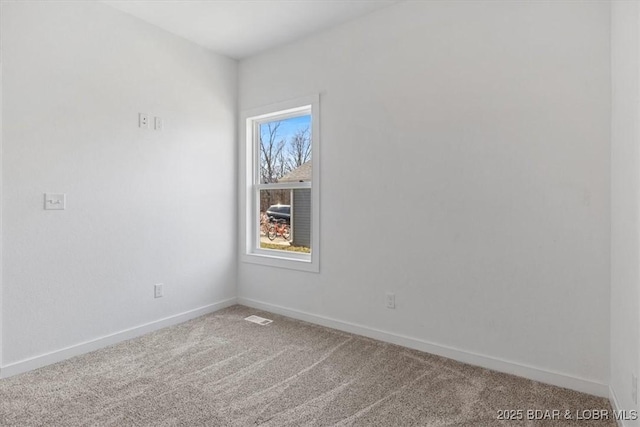 spare room featuring carpet flooring, baseboards, and visible vents