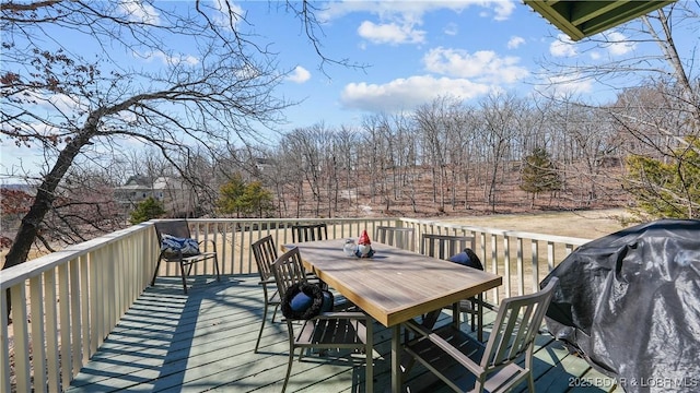 wooden terrace with outdoor dining area and a grill