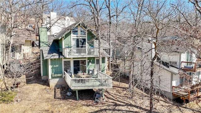 rear view of property with a balcony and a chimney