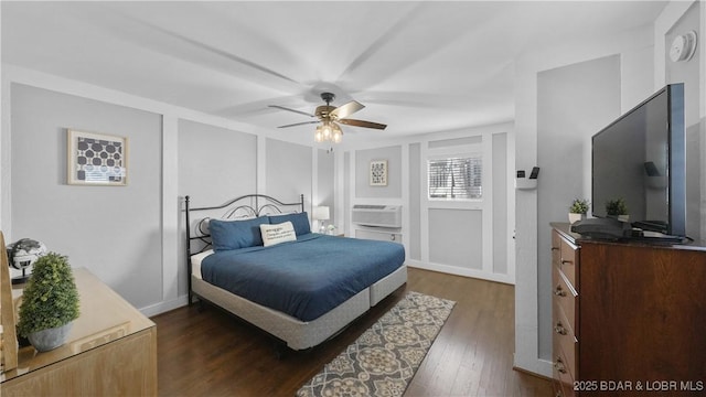 bedroom with dark wood finished floors, a decorative wall, a wall mounted air conditioner, and a ceiling fan