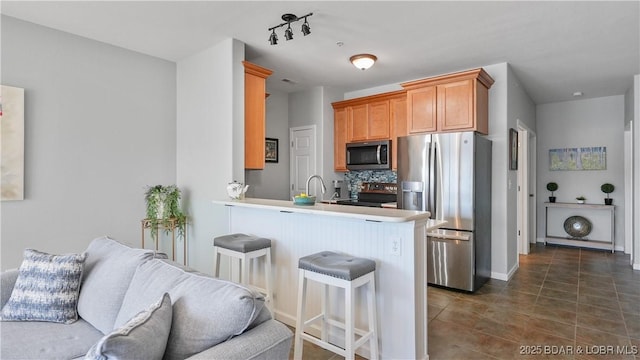 kitchen with backsplash, open floor plan, appliances with stainless steel finishes, a peninsula, and a kitchen breakfast bar