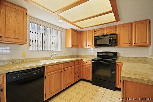 kitchen featuring black appliances, light countertops, backsplash, and a sink