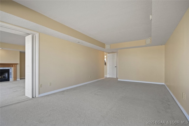 spare room featuring carpet, baseboards, and a tile fireplace