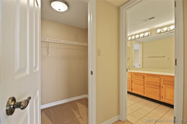 bathroom featuring tile patterned floors, visible vents, a textured ceiling, baseboards, and vanity